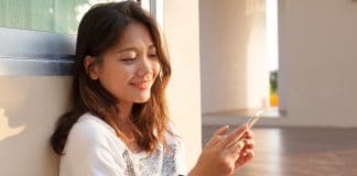 beautiful young and teen woman looking to mobile phone with smiling face in home outdoor use for chat talking and internet on line connecting technology